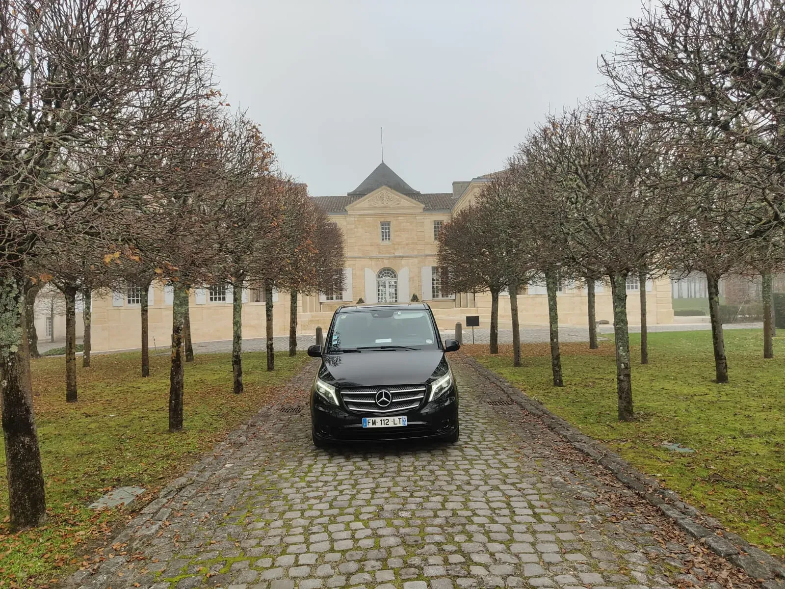 Van Mercedes Classe V avec chauffeur privé devant un château de la région bordelaise
