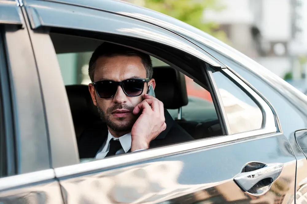 Homme d'affaires au téléphone à l'arrière d'une berline avec chauffeur